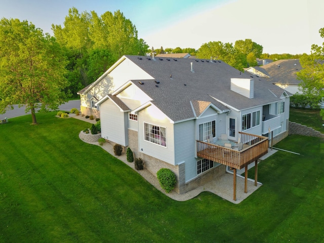 rear view of property with a yard, a deck, and roof with shingles