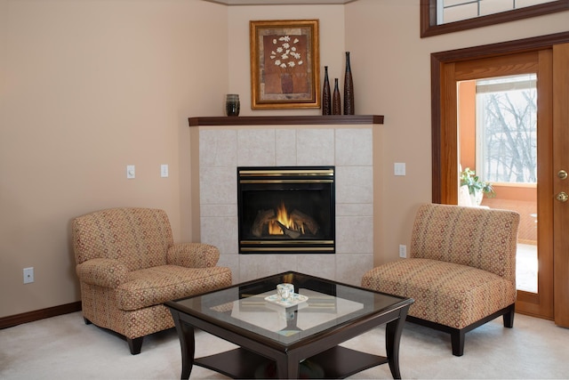 sitting room with baseboards, light colored carpet, and a fireplace