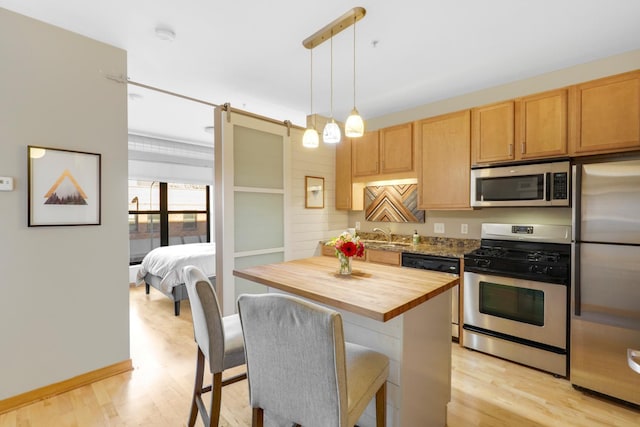 kitchen featuring light hardwood / wood-style flooring, wooden counters, hanging light fixtures, stainless steel appliances, and a kitchen island