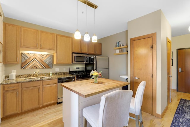 kitchen with sink, wooden counters, decorative light fixtures, a center island, and appliances with stainless steel finishes