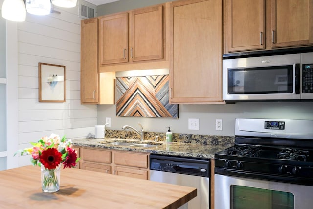 kitchen with appliances with stainless steel finishes, butcher block counters, sink, and light brown cabinetry