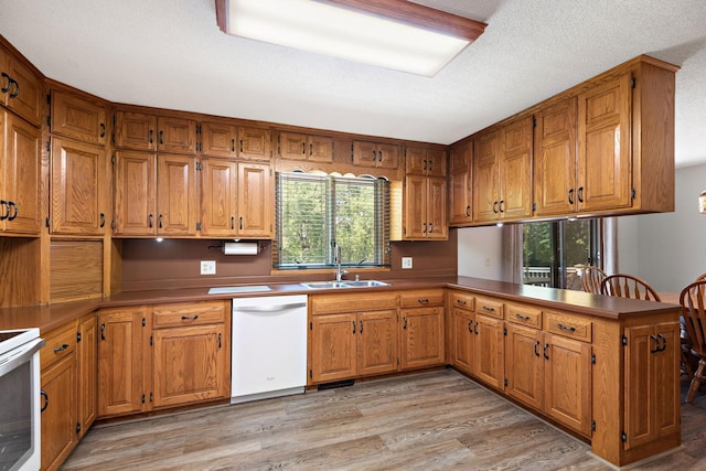 4879 Mayelin Ave NE, Saint Michael, MN 55376 - kitchen with white appliances, a peninsula, light wood-style flooring, and brown cabinetry