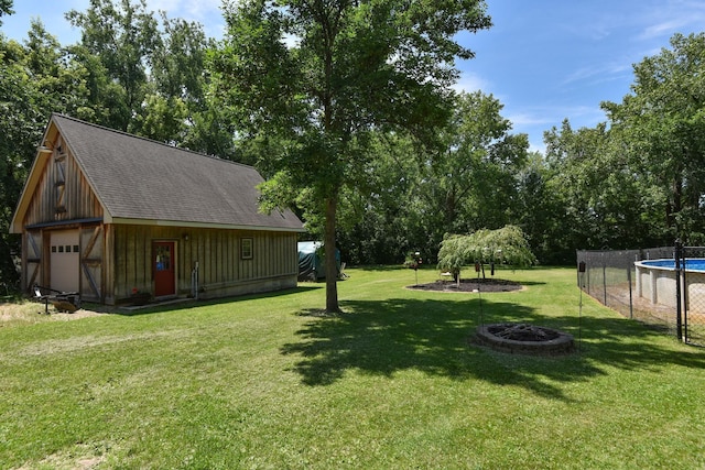 4879 Mayelin Ave NE, Saint Michael, MN 55376 - view of grassy yard featuring an outdoor fire pit, an outbuilding, a garage, and view of wooded area