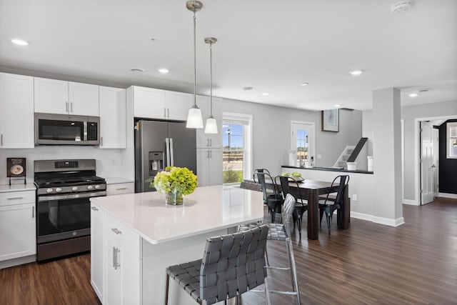 kitchen with white cabinetry, decorative light fixtures, a center island, and appliances with stainless steel finishes