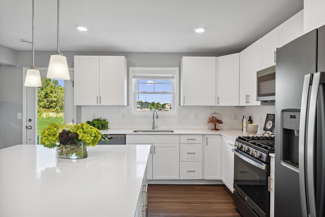 kitchen featuring pendant lighting, sink, appliances with stainless steel finishes, white cabinetry, and tasteful backsplash