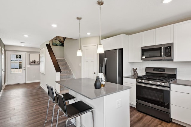 kitchen with appliances with stainless steel finishes, pendant lighting, white cabinetry, a kitchen breakfast bar, and decorative backsplash