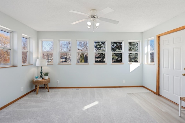 unfurnished sunroom featuring plenty of natural light and a ceiling fan