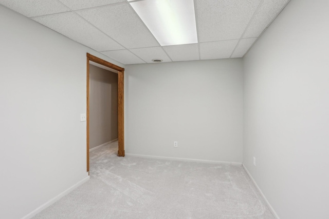 unfurnished room with a drop ceiling, light colored carpet, and baseboards