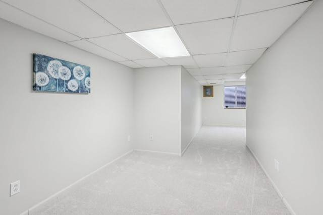 interior space featuring a paneled ceiling, carpet, and baseboards