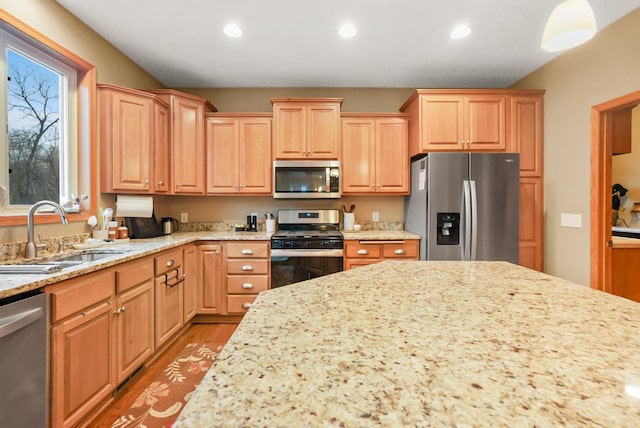 kitchen featuring light stone counters, sink, light hardwood / wood-style floors, and appliances with stainless steel finishes