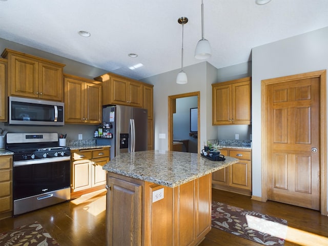 kitchen featuring appliances with stainless steel finishes, a center island, brown cabinetry, and decorative light fixtures