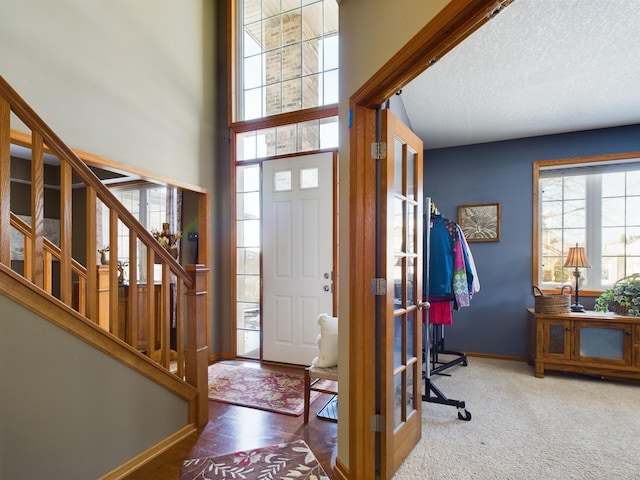 entrance foyer featuring stairs, a high ceiling, a textured ceiling, and baseboards