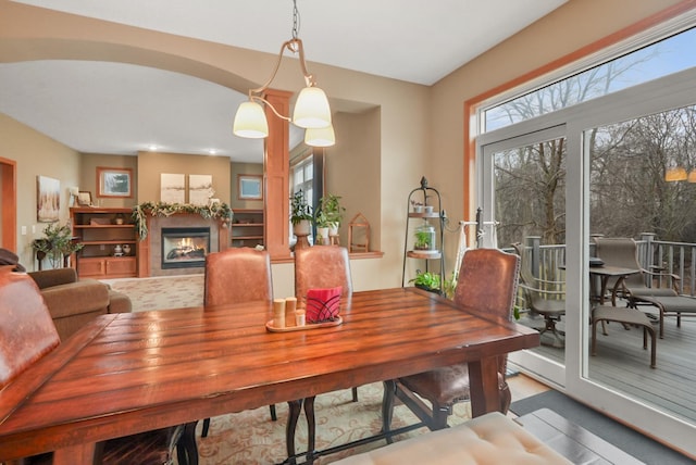 dining room with arched walkways and a glass covered fireplace