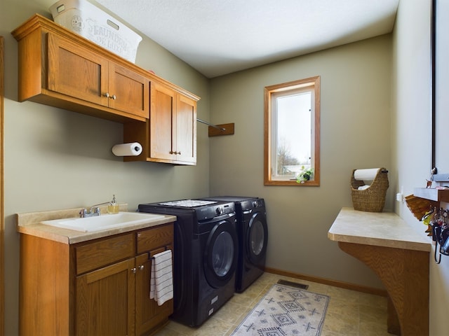 washroom with independent washer and dryer, a sink, cabinet space, and baseboards