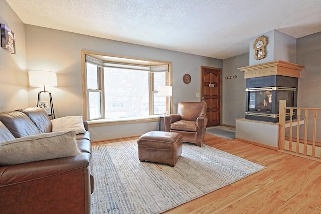 living room featuring wood-type flooring, a textured ceiling, and a multi sided fireplace