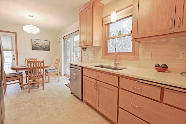 kitchen featuring sink, hanging light fixtures, backsplash, stainless steel dishwasher, and light brown cabinets