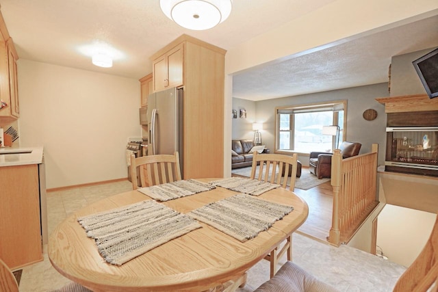 dining area featuring sink, a textured ceiling, and a multi sided fireplace