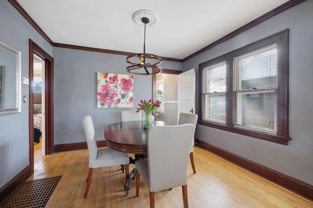 dining room with crown molding, an inviting chandelier, and light hardwood / wood-style flooring