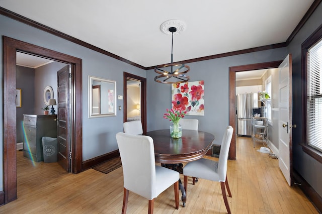 dining area featuring ornamental molding, a chandelier, and light hardwood / wood-style floors