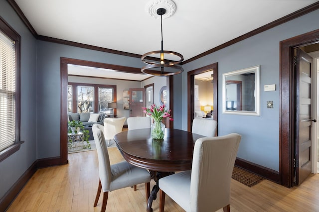 dining area featuring crown molding, a notable chandelier, and light hardwood / wood-style flooring