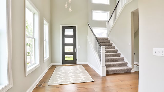 entryway with a towering ceiling and light hardwood / wood-style flooring