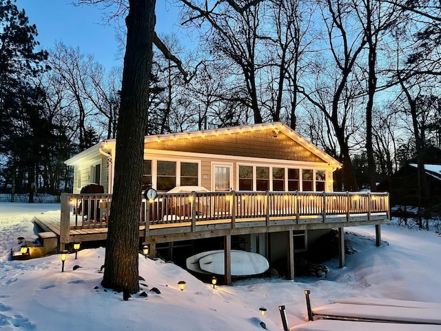 snow covered back of property featuring a deck