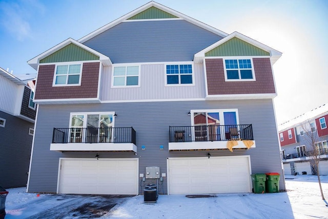 snow covered rear of property featuring central AC and a balcony