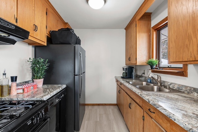 kitchen with black dishwasher, sink, light hardwood / wood-style floors, and fridge