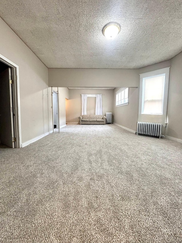 unfurnished room with carpet floors, radiator heating unit, and a textured ceiling