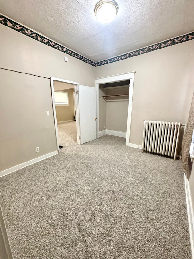 unfurnished bedroom with radiator, light colored carpet, a closet, and a textured ceiling