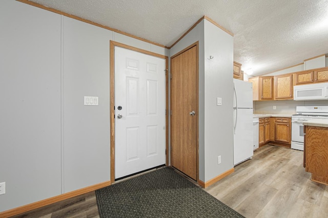 kitchen with white appliances, vaulted ceiling, a textured ceiling, and light wood-type flooring