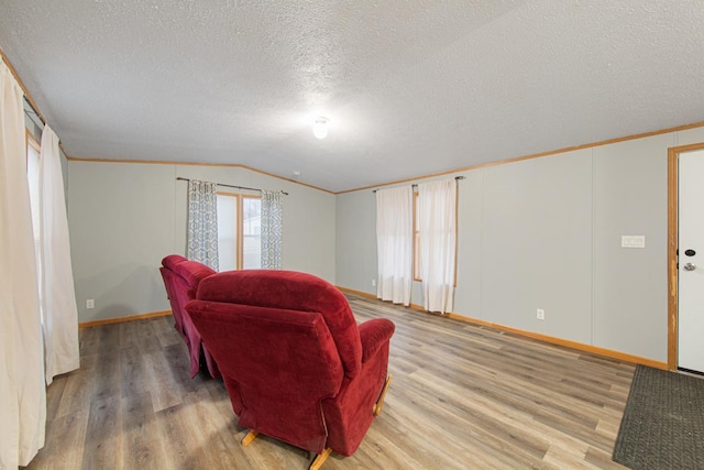 living room featuring lofted ceiling, crown molding, wood-type flooring, and a textured ceiling