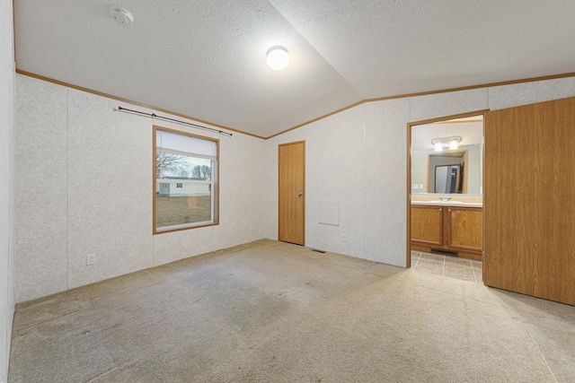 carpeted empty room featuring crown molding, lofted ceiling, sink, and a textured ceiling