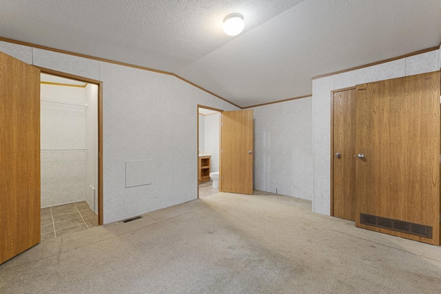 unfurnished bedroom featuring crown molding, light colored carpet, vaulted ceiling, and a textured ceiling