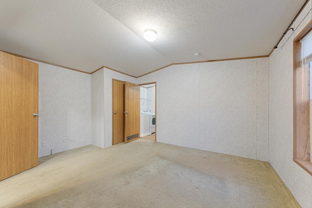 carpeted spare room with vaulted ceiling, crown molding, washing machine and dryer, and a textured ceiling