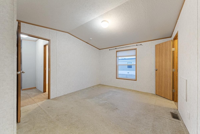 carpeted empty room featuring crown molding, lofted ceiling, and a textured ceiling