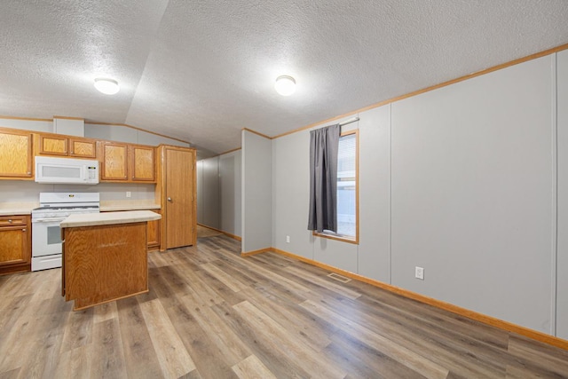 kitchen with vaulted ceiling, a center island, white appliances, and light hardwood / wood-style flooring