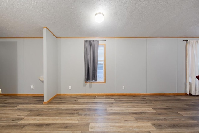 unfurnished room featuring crown molding, wood-type flooring, and a textured ceiling