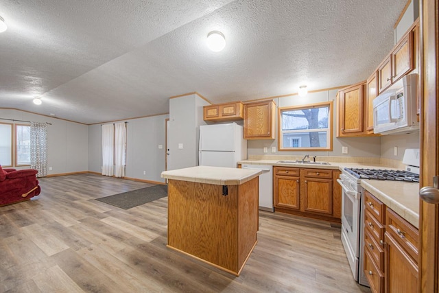 kitchen with a kitchen island, sink, light hardwood / wood-style floors, a healthy amount of sunlight, and white appliances