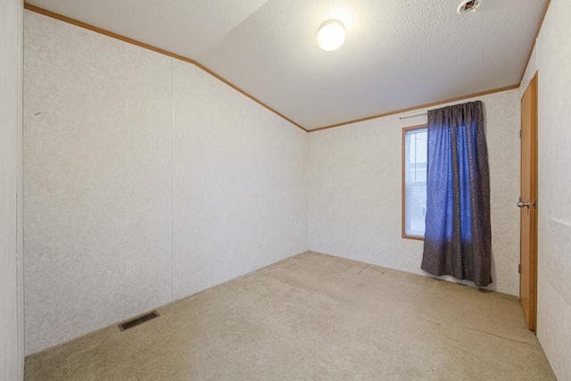 carpeted spare room featuring crown molding, vaulted ceiling, and a textured ceiling