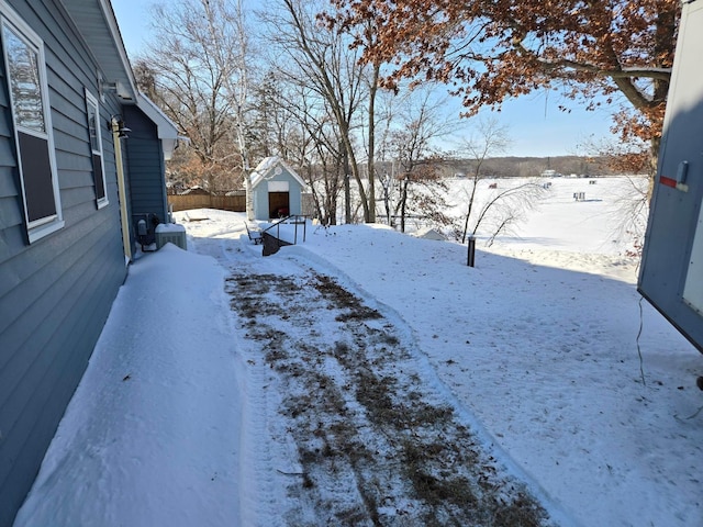 yard covered in snow featuring central AC unit and a storage shed