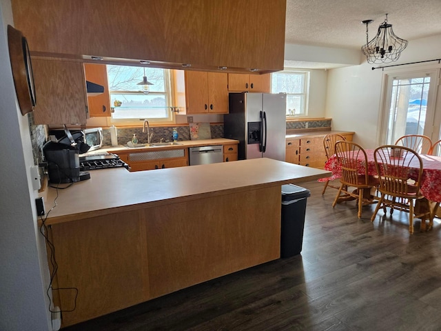 kitchen with sink, kitchen peninsula, hanging light fixtures, and stainless steel appliances