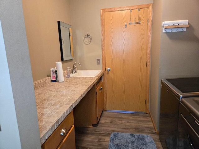 bathroom with washing machine and dryer, vanity, and hardwood / wood-style flooring