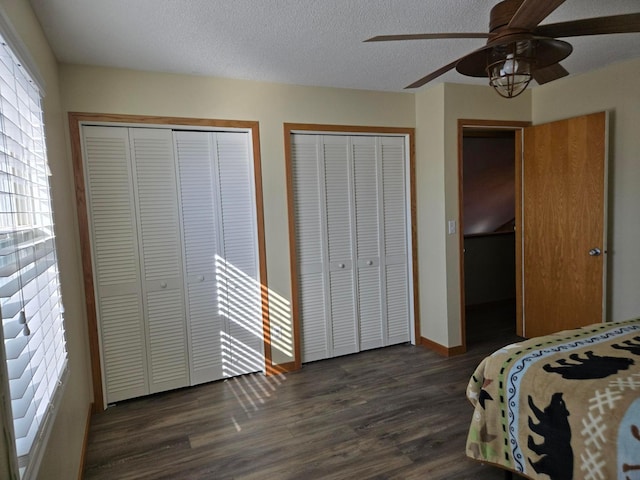 bedroom with ceiling fan, a textured ceiling, multiple closets, and dark hardwood / wood-style floors