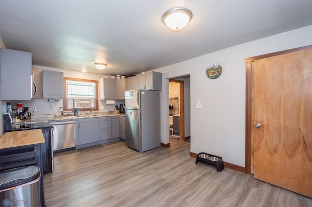 kitchen featuring light wood-type flooring, sink, gray cabinets, and appliances with stainless steel finishes