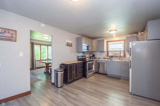 kitchen with gray cabinets, appliances with stainless steel finishes, sink, and light wood-type flooring