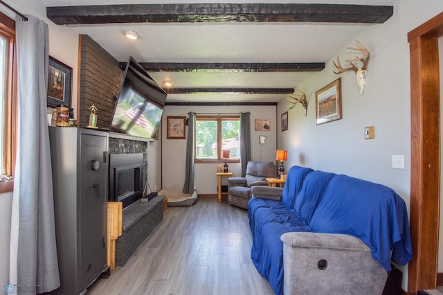 living room featuring beam ceiling, wood-type flooring, and a large fireplace