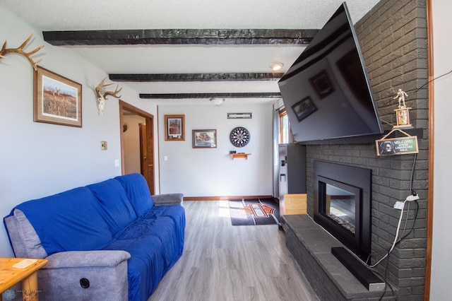 living room featuring hardwood / wood-style flooring, a brick fireplace, a textured ceiling, and beamed ceiling