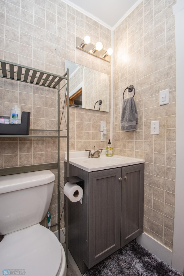 bathroom with vanity, ornamental molding, tile walls, and toilet