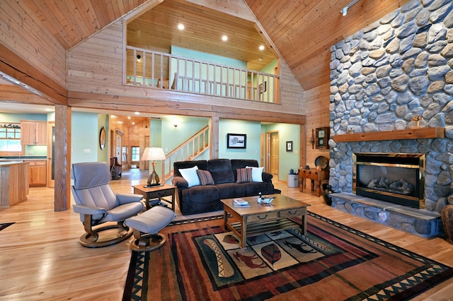 living room with wood ceiling, light hardwood / wood-style flooring, a stone fireplace, and vaulted ceiling